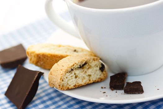 Biscotti and chocolate with a cup of coffee on gingham tablecloth