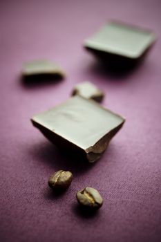 Chocolate with coffee beans on violet tablecloth