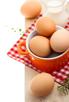 Fresh brown eggs with milk on red gingham checked tablecloth