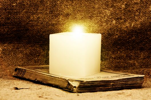 candle on an old book
