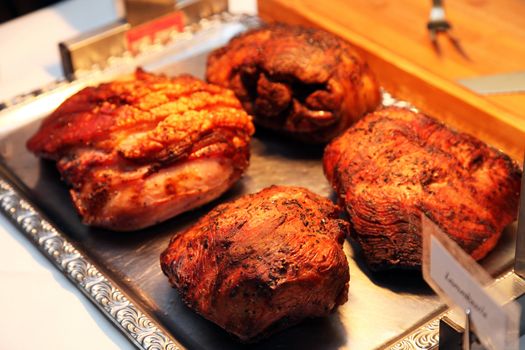 Four cuts of delicious browned roast meat on a buffet table at a catered event or celebration waiting to be carved for the guests