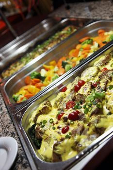 Large stainless steel dishes of delicious freshly prepared hot vegetables displayed on a buffet table at a catered event or celebration