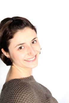 Closeup head portrait of an attractive young brunette woman with a friendly smile standing sideways looking at the camera isolated on white with copyspace