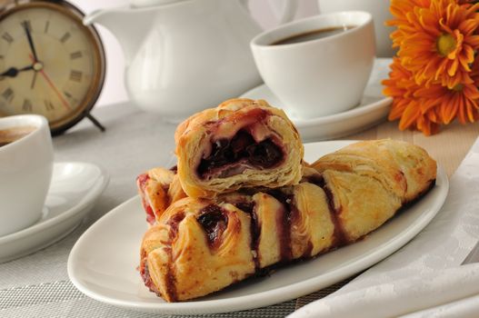 A piece of strudel with cherries with a morning cup of coffee