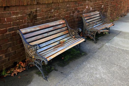 Two wooden benchs against a brick red wall 