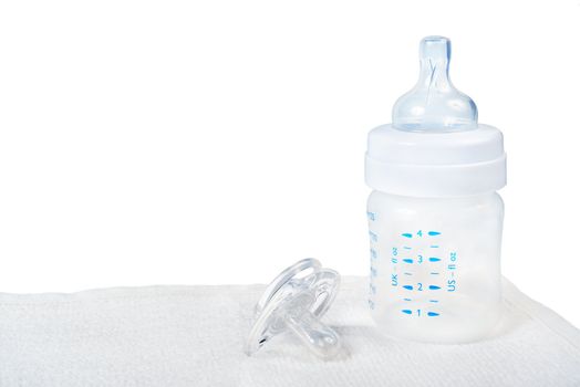 Baby bottle and pacifier on towel.