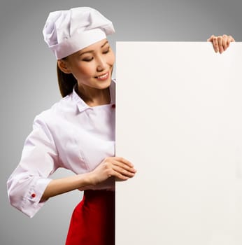 female chef holding a poster for text, look at the poster and smiling