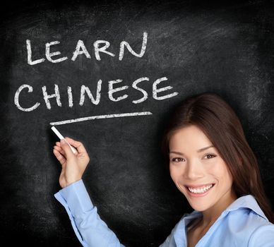 Chinese language learning. Woman teacher or student writing learn chinese on blackboard / chalkboard. Chinese Asian / Caucasian mixed race woman.
