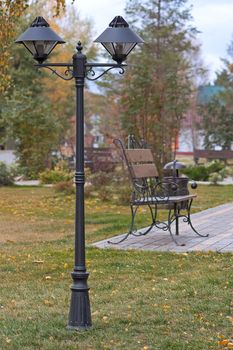 Iron lantern and bench in park in autumn, Russia.
