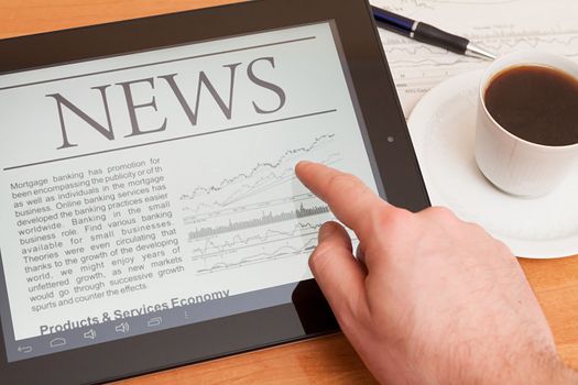 Tablet PC shows latest news on screen, which lying on work place. 