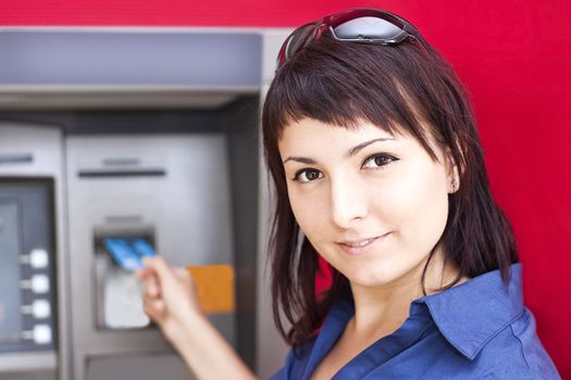 Beautiful woman using credit card, she is withdrawing money from an ATM machine.