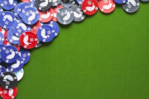 Colorful gambling chips on green felt background with copy space