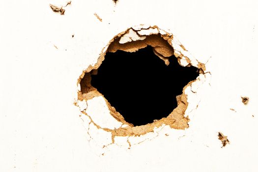 Hole in the fibreboard on black background.