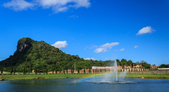 Rainbow in water fountain and green mountain at Pattaya, Thailand.