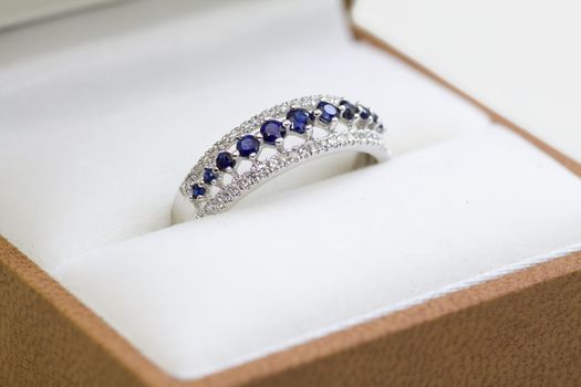 A white gold engagement ring with diamond and sapphire in a box.