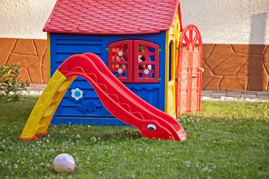 Plastic outdoor slide and toy house in a garden