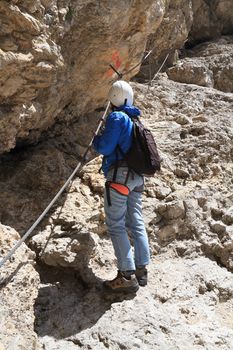 	female climber ascending rocks on via ferrata pathway, Italian Dolomites