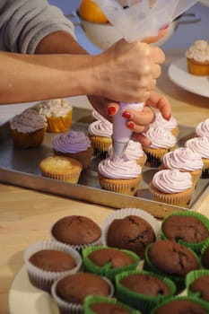 Nice girl hand decorating some tastefully cupcakes