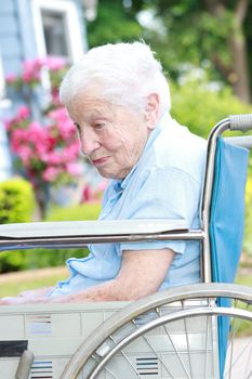 Senior lady in wheel chair in front of house with pink flowers