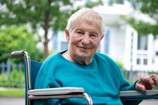 Happy senior lady in wheelchair relaxing outside