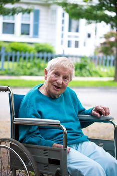 Happy senior lady in wheelchair in front of house