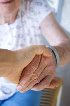 Caregiver holding seniors hand on porch