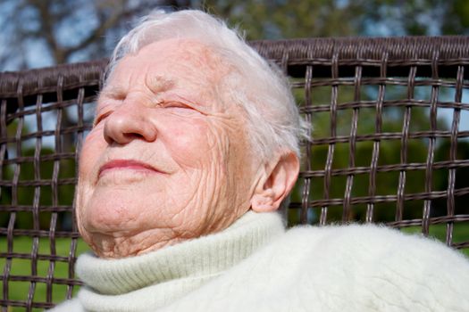 Portrait of senior woman relaxing outside on garden chair