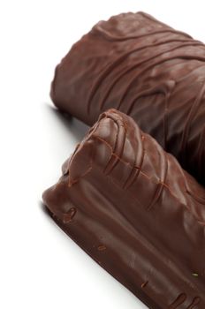 Delicious Biscuit Swiss Rolls with Chocolate Glaze closeup on white background