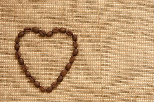 love symbol made of coffee beans on sack background