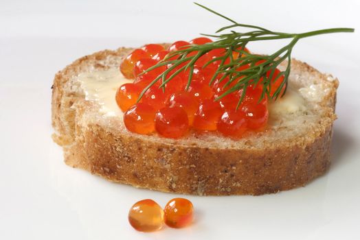 Salmon caviar on fresh whole-grain baguette with butter and dill isolated