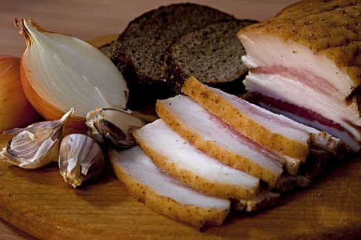 Sliced salted pork lard with garlic and onion lying on desk