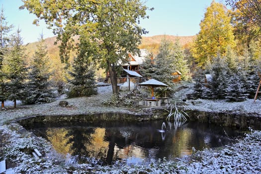 Mountain garden with a pond covered by snow