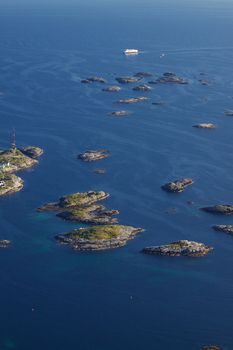 Large cruising ship passing by tiny islands on norwegian coast near town of Henningsvaer on Lofoten islands
