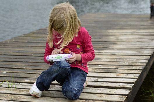 Modern young girl playing computer game in nature