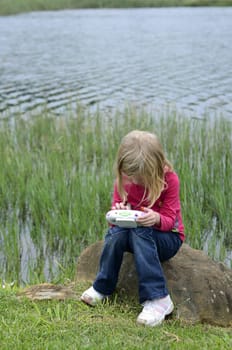 Modern young girl playing computer game in nature