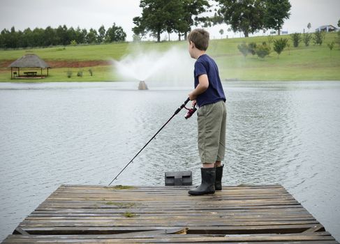 Boy bass fishing on dam or lake pier