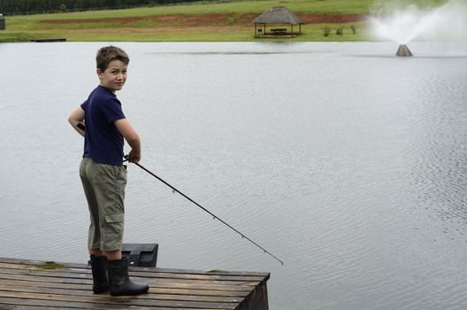 Boy bass fishing on dam or lake pier