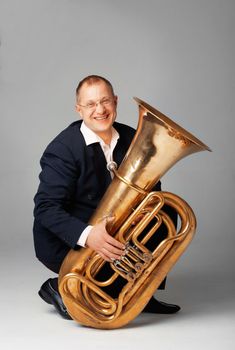 Portrait  of a  smiling young tubaist with his instrument