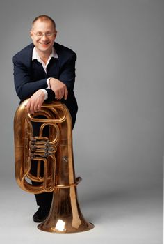 Portrait  of a  smiling young tubaist with his instrument