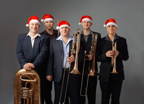 Portrait of a five young musicians with  instruments. They are dressed in a cap of Santa