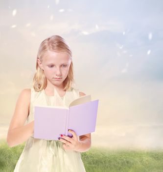 Little Blond Girl Reading a Book in the Field