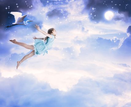 Little girl flying into the blue night sky with white egret