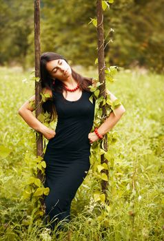 Portrait of beautiful model in black on nature background, posing.