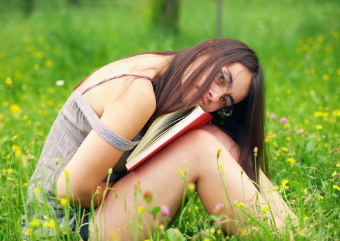 Young  female student holding a book  over nature background 
