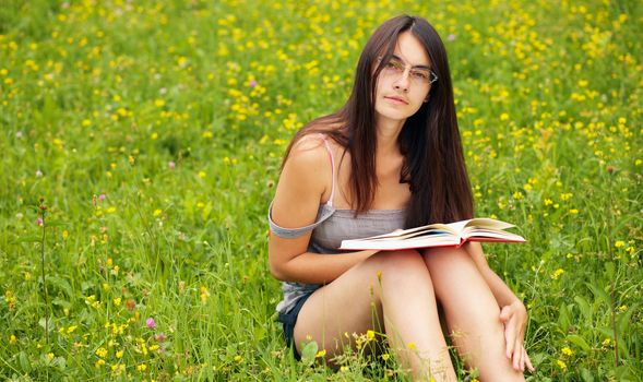 Young  female with a book  on a green meadow