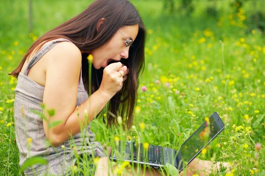 Shocked Young woman using her laptop outdoors.