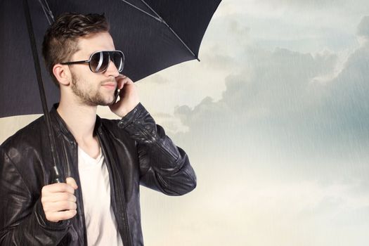 Stylish Man Holding an Umbrella and Talking on His Phone
