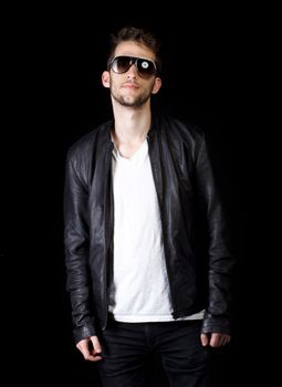 Portrait of young handsome man wearing sunglasses on black background