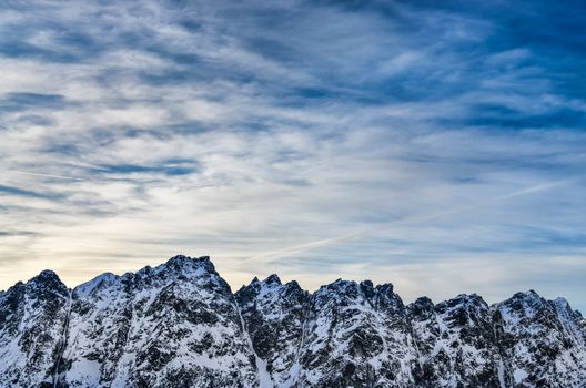 Winter mountains landscape with blue cloudy sky