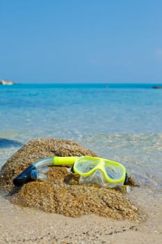 Yellow snorkel and mask on the beach. Vertical view